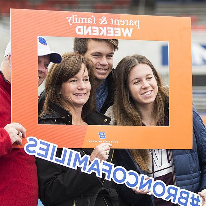 Student with family posing on blue turf